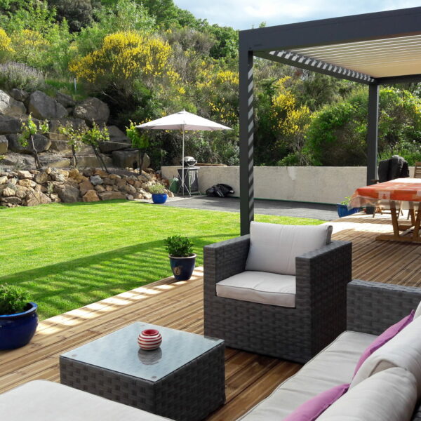 Terrasse en bois de pin posée sur une structure Terrassteel avec salon de jardin et pergola